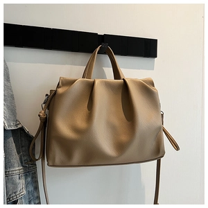 Detail of khaki pleated bucket bag with soft faux leather texture and top handle