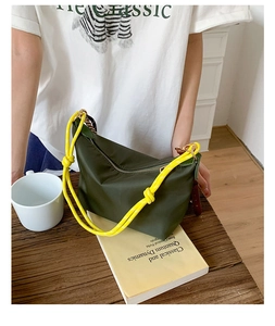 Detail of dark green nylon bag featuring a vibrant yellow knotted shoulder strap and gold hardware