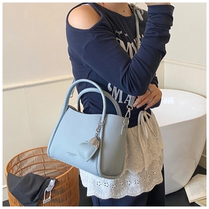 Close-up of light blue lychee pattern leather handbag with heart-shaped charm and handle