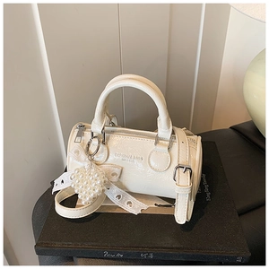 Detail of cream retro cylinder bag with pearl heart pendant and lace trim decoration