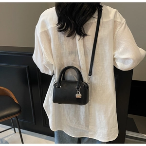 Detailed shot of black pebbled leather mini Boston bag with silver padlock and long strap