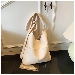 Detail einer cremeweißen Hobo-Tasche aus Leder mit feiner Lychee-Narbung und breitem Gurt