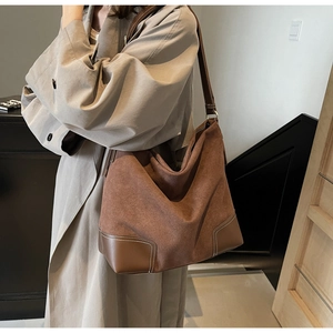 Detail of vintage brown suede tote bag with contrast white stitching and smooth leather straps