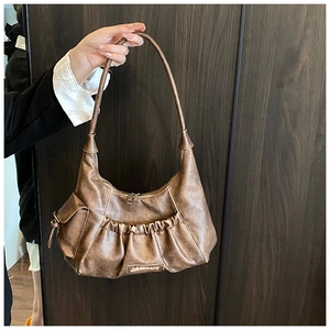 Detail of vintage brown leather hobo bag featuring ruched texture and MISMA metal logo