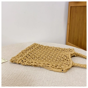 Close-up of beige woven tote bag showing hollow mesh pattern and braided handles