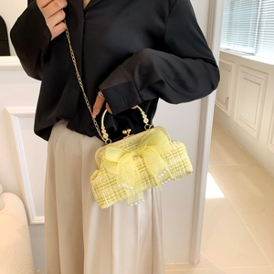 Detailed close-up of yellow tweed shell bag with pearl accents and tulle bow
