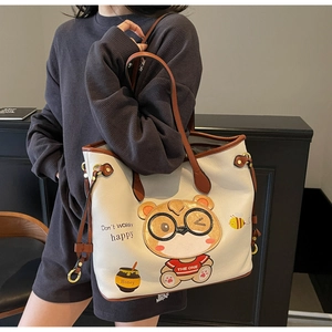 Detail of white tote bag featuring bear print with contrast brown trim and leather texture