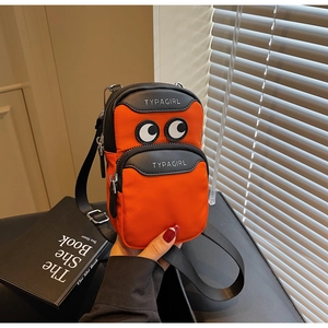 Detail of mini orange canvas phone bag featuring cartoon eyes and adjustable strap
