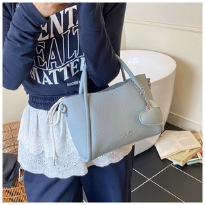 Detailed texture of light blue pebble leather bag with heart charm and metal chain
