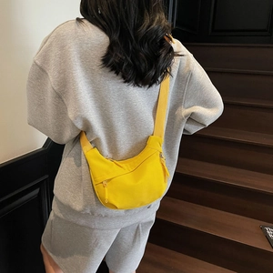 Bright yellow half-moon nylon crossbody bag shown from the back on a model with wide strap