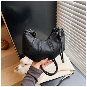 Detail der schwarzen Hobo-Tasche mit Lychee-Struktur und einem geknoteten Schultergurt