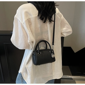 Detail of black pebbled leather pillow bag with silver lock and detachable strap