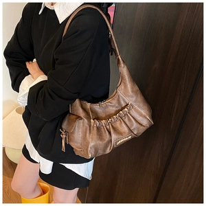 Detailed view of brown vintage pleated baguette bag with side pocket and logo plate