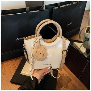 Detail of white bucket bag with round handle, plush bear charm and ribbon decor
