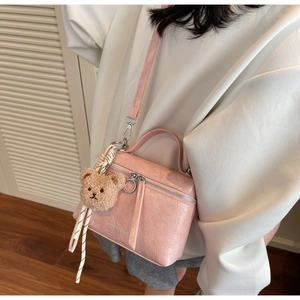 Pink pleated leather vanity bag styled as a crossbody with a cute plush bear pendant