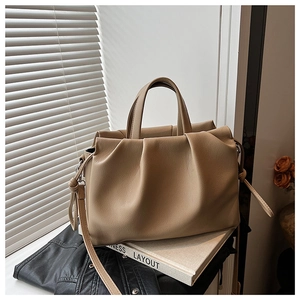 Detail of khaki pleated handbag with lychee texture grain and knot decoration