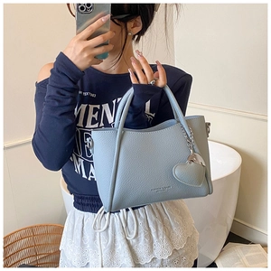 Close-up of light blue lychee leather tote bag with heart charm and silver chain details