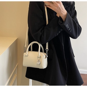 Detail of white lychee-patterned leather handbag featuring a silver padlock charm