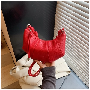 Makro-Detail der roten Mondsichel-Tasche aus Leder mit Litschi-Körnung und vertikalen Nähten