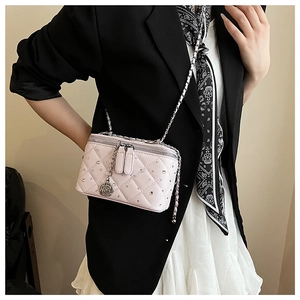 Detail of pink quilted box bag with crystal studs and rose pendant worn with chain strap