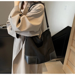Detail of black matte tote bag featuring contrast white stitching and leather corners