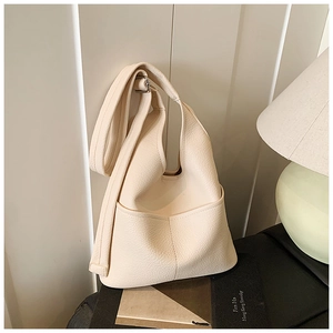 Detailaufnahme der cremefarbenen Eimer-Tasche aus Leder mit Lychee-Narbung und Gurt