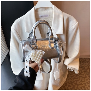 Close-up of silver cylinder bag with pearl heart charm and lace bow detail