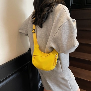 Detail of a bright yellow nylon crescent crossbody bag with metal zippers and black strap