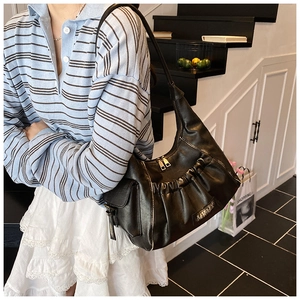 Detail of black pleated leather underarm bag with metallic zipper and vintage texture