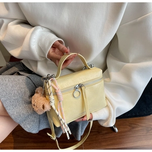 Detail of yellow pleated leather bucket bag with cute brown bear charm and metal zipper