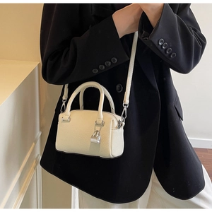 Close-up of cream Boston mini handbag with lychee grain leather and silver lock charm