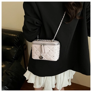 Detail of light pink quilted box bag with silver chain and camellia flower pendant