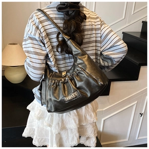 Detailed view of black pleated hobo bag with sleek finish and MKMX metal logo