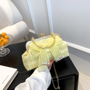 Detail of yellow tweed shell bag featuring sheer bow, pearls, and gold ring handle