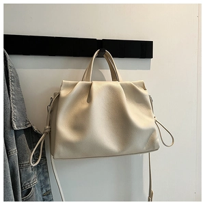 Detailed view of cream pleated crossbody bag with pebble texture hanging on a black hook