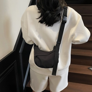 Detail of adjustable strap and plastic buckle on black nylon crossbody dumpling bag
