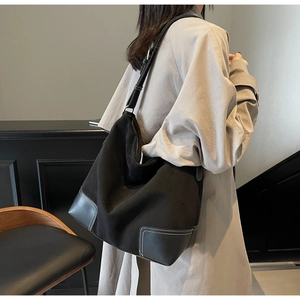 Detail of vintage black suede hobo bag with contrast white stitching and adjustable strap