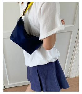 Detail of dark blue nylon handbag featuring leather flap and woven shoulder strap