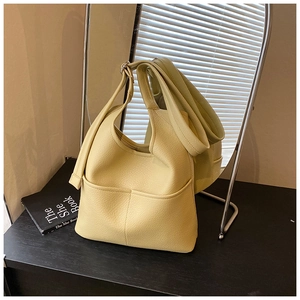 Detailansicht hellgelbe Hobo-Tasche aus Litchi-Leder mit breitem Schultergurt auf Tisch