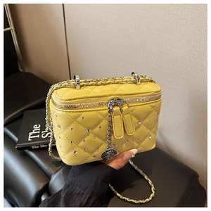Detail of yellow quilted box bag with diamond embellishments and a rose pendant