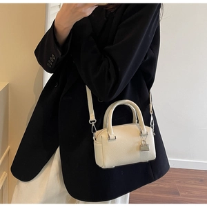 Detailed view of beige crossbody pillow bag with silver lock charm on a model