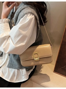 Bolso de hombro cuadrado beige con cierre dorado lucido en un conjunto de diario