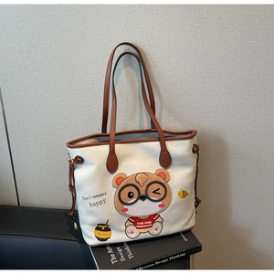 Close-up of beige tote bag with cute bear print and textured lychee leather grain