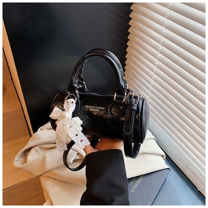 Detail of vintage black patent leather cylinder bag with lace bow and pearl charm