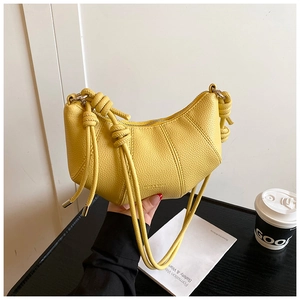 Detail einer gelben Halbmond-Tasche mit Litschitextur-Leder und Knotengurt-Design