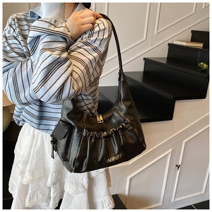 Detail of black pleated faux leather underarm bag with side pocket and silver logo plaque