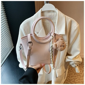 Detail of light pink patent leather bucket bag with cute bear charm and scarf accessory