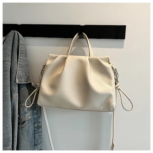 Detailed view of cream pleated crossbody bag featuring drawstring knots and leather texture