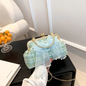Close-up of blue tweed bag with large mesh bow and pearl details in home setting