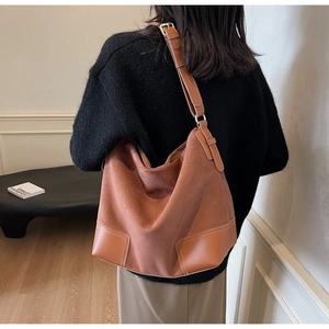 Detail of tan suede tote bag featuring leather corner patches and white contrast stitching